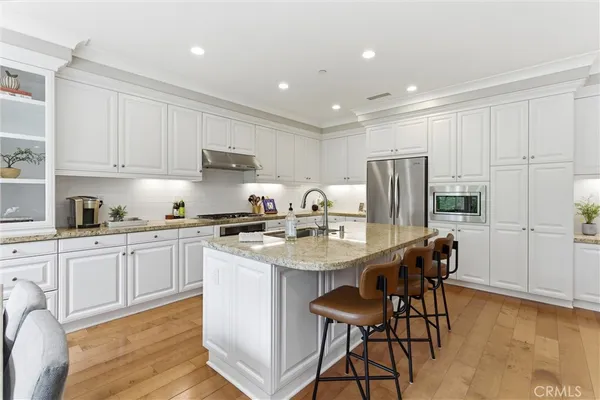 a kitchen with stainless steel appliances granite countertop a table chairs sink refrigerator and cabinets