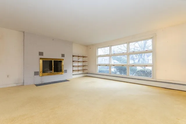 an empty room with a fireplace and large window