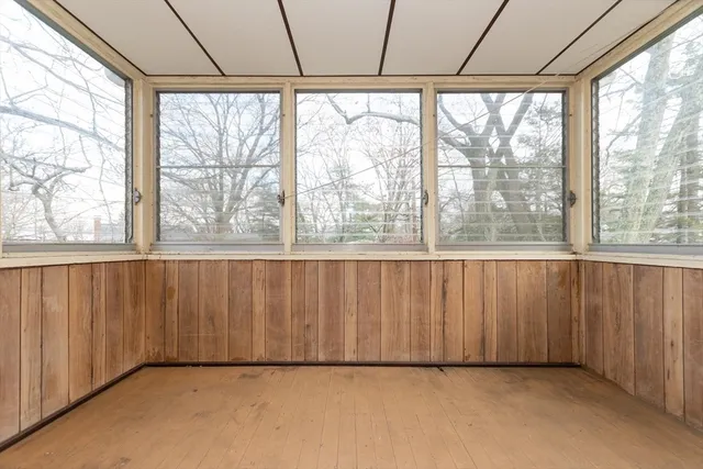 a view of an empty room with a window and hardwood