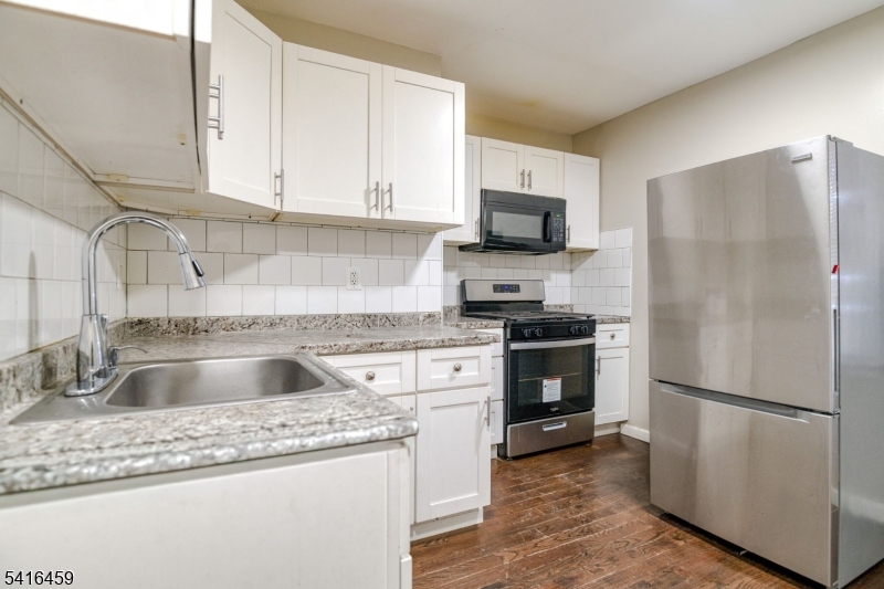 a kitchen with granite countertop a refrigerator stove and sink
