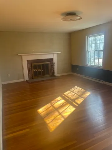 a view of empty room with wooden floor and fireplace
