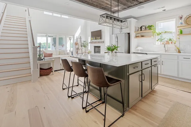 a kitchen with stainless steel appliances a table chairs refrigerator and wooden floor