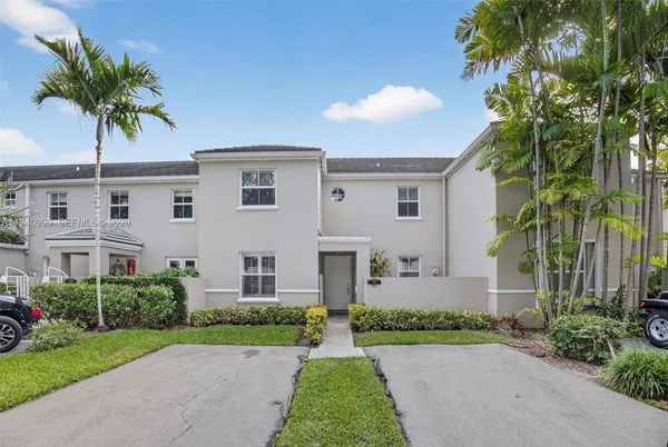 a front view of a house with a garden and palm trees