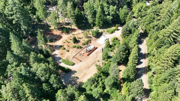 an aerial view of residential house with outdoor space and trees all around