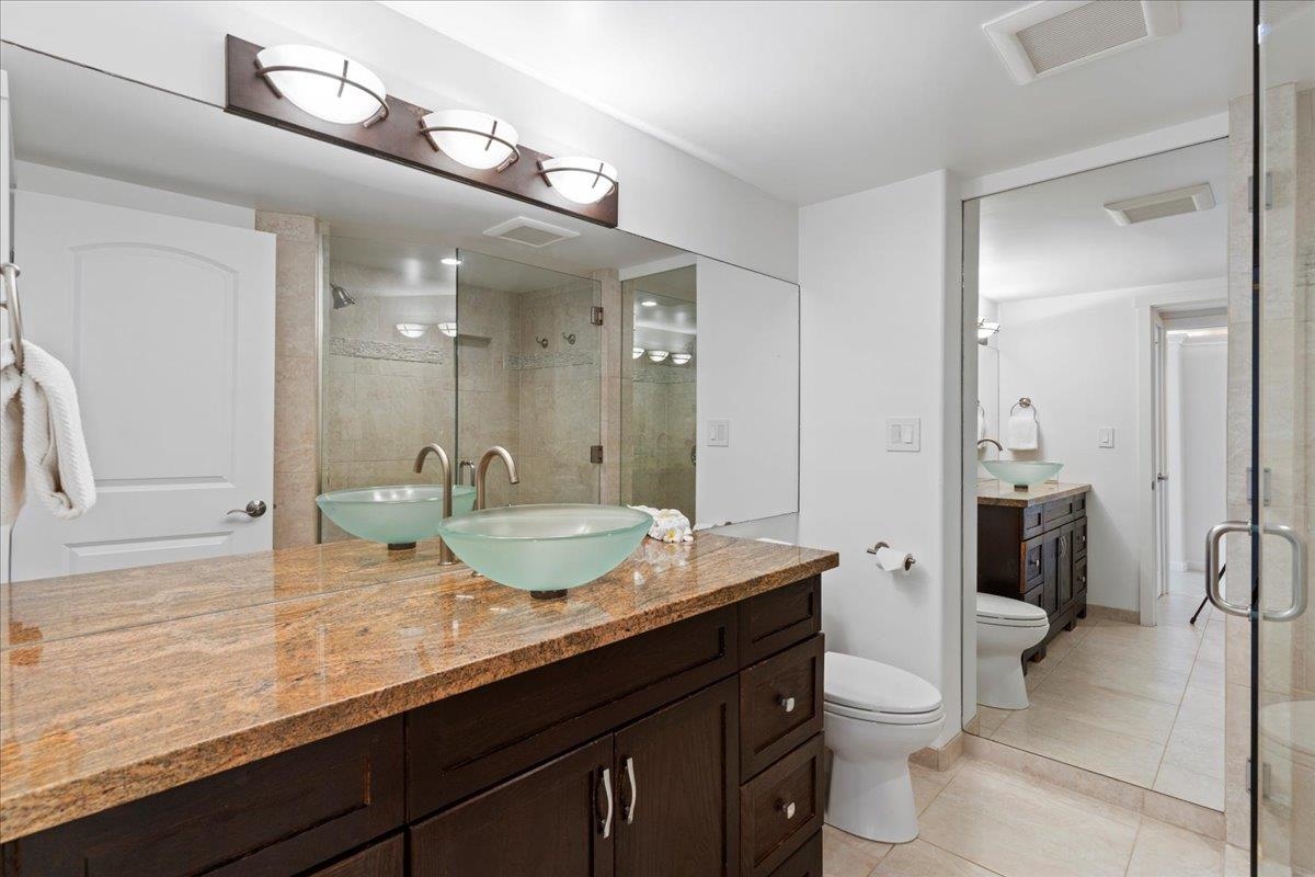 4850 Makena Alanui Road, Unit E205 Kihei, HI 96753 - Photo 28 of 45 a bathroom with a granite countertop sink a toilet a mirror and shower