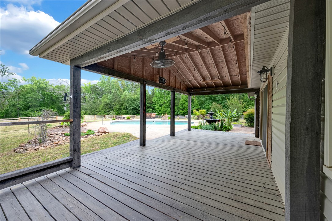 433 Latham Road Easley, SC 29640 - Photo 4 of 50 An inviting covered deck offers ample space for outdoor living, overlooking a refreshing pool and landscaped yard.