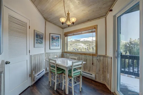 a dining room with wooden floor a chandelier a wooden table and chairs