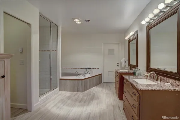 a bathroom with a granite countertop double vanity sink a mirror and a bathtub