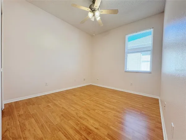 an empty room with a window and a ceiling fan