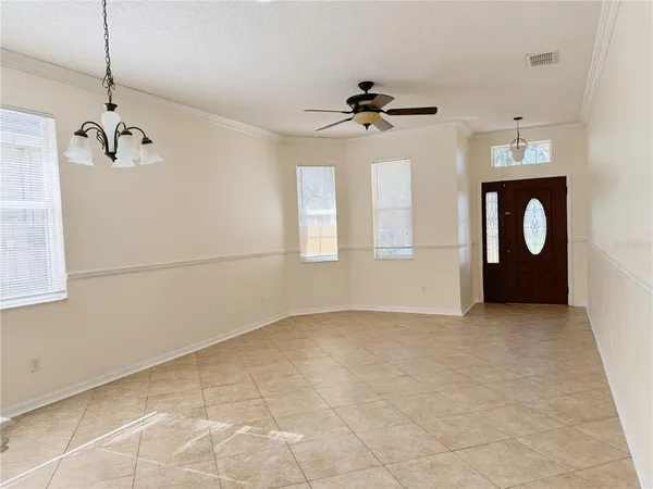 a view of an empty room with a window and chandelier fan