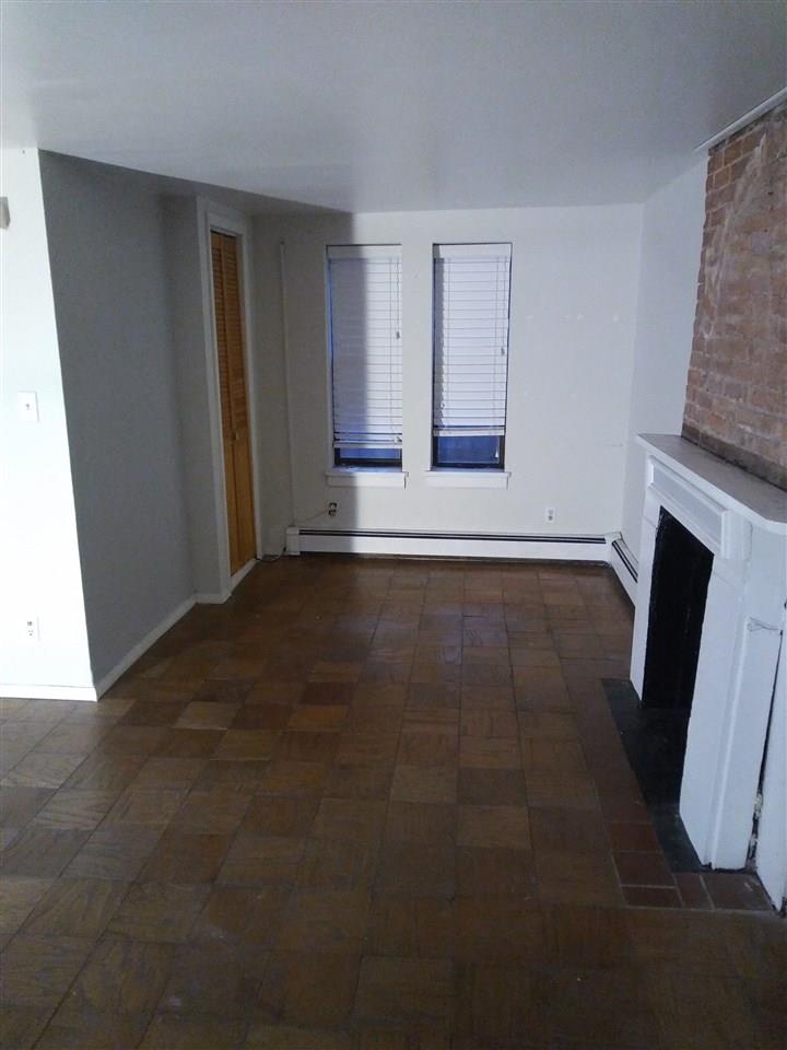 220 Garden Street, Unit 1(GRND) Hoboken, NJ 07030 - Photo 4 of 9 a view of an empty room with wooden floor and a fireplace