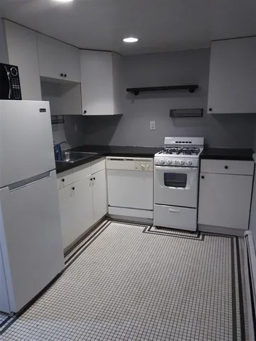 a white kitchen with granite countertop stainless steel appliances