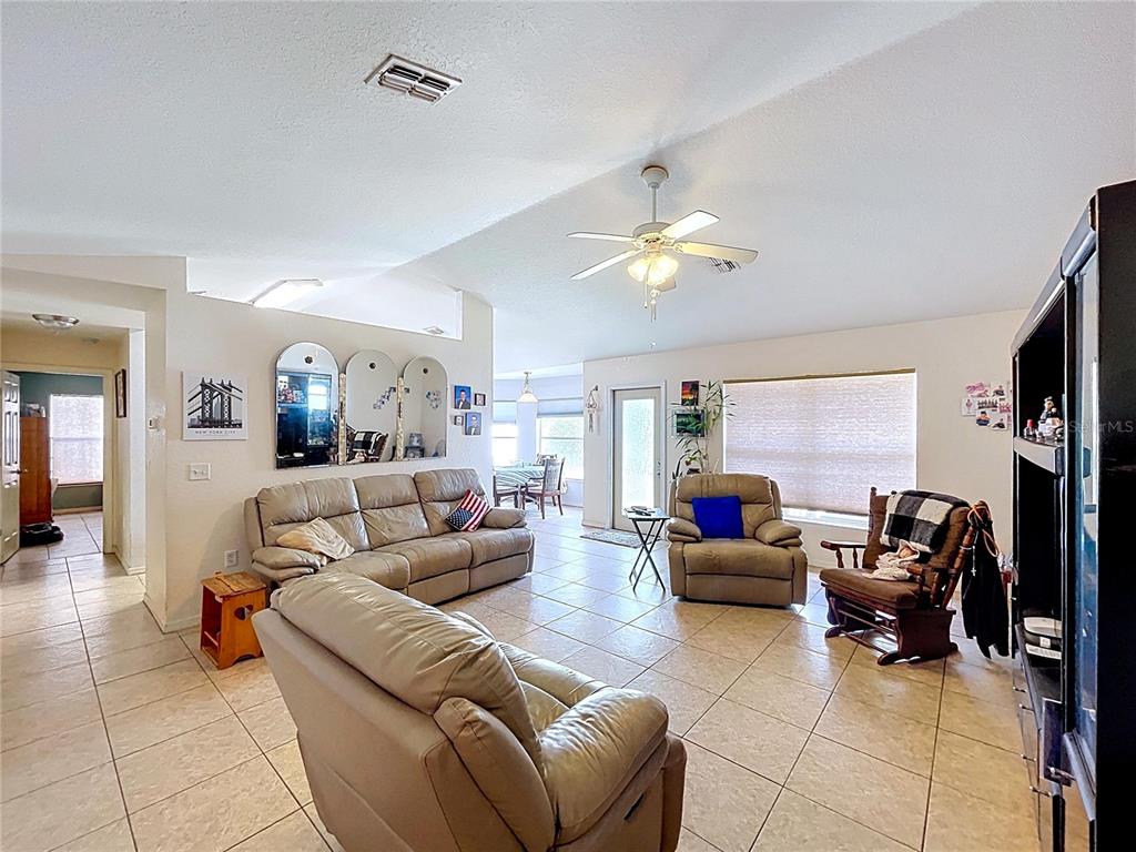 4372 Odin Street Spring Hill, FL 34608 - Photo 8 of 38 a living room with furniture a chandelier and a flat screen tv