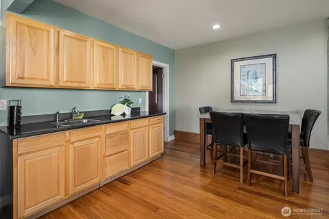 a kitchen with stainless steel appliances granite countertop a table chairs sink and cabinets