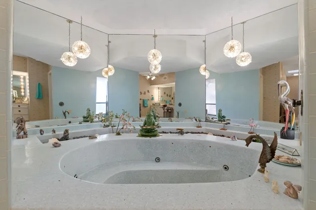 a spacious bedroom with a bed a dresser and flowerpot