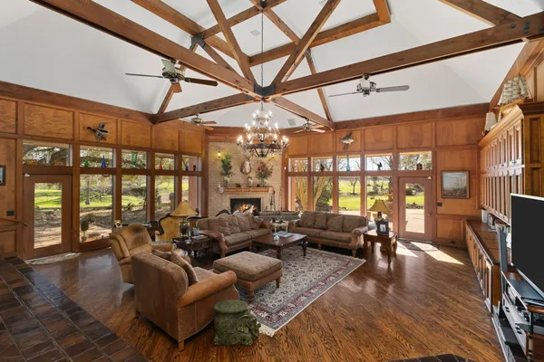 a living room with furniture a chandelier and a dining table with wooden floor