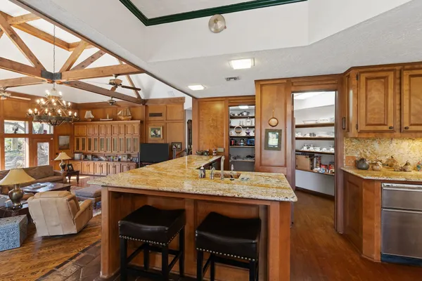 a kitchen with stainless steel appliances kitchen island granite countertop a table chairs and a refrigerator