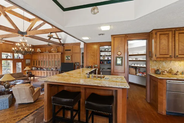 a kitchen with stainless steel appliances kitchen island granite countertop a table chairs and a refrigerator