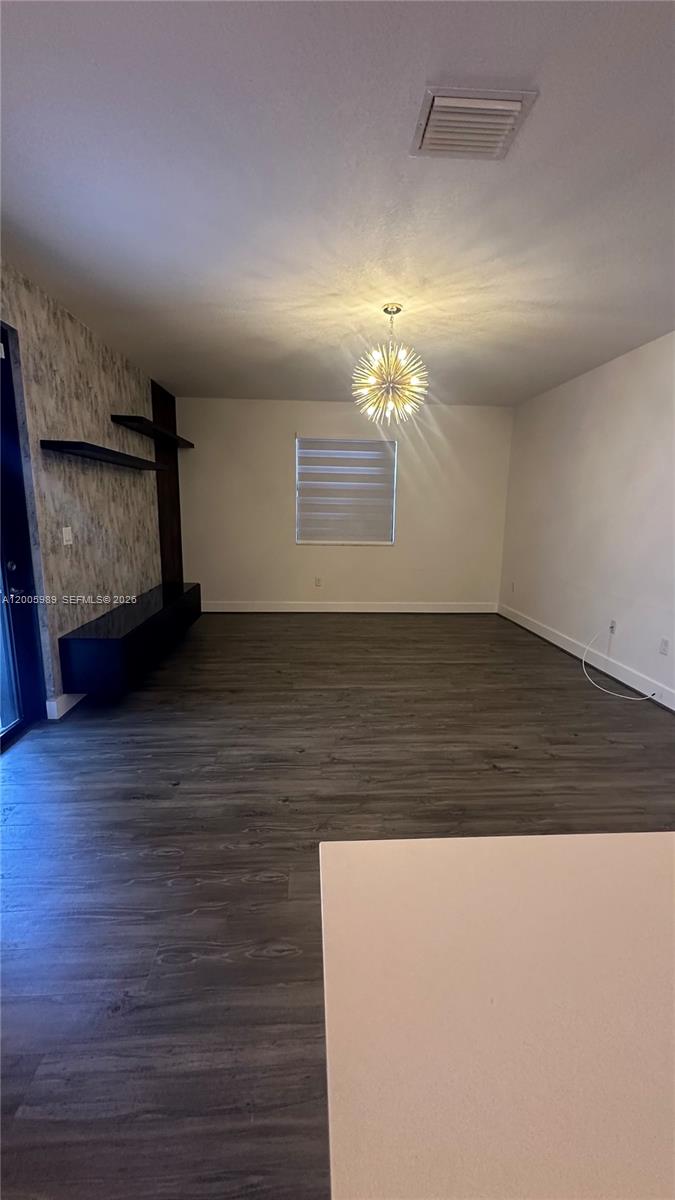 3423 West 110th Street Hialeah, FL 33018 - Photo 5 of 42 a view of an empty room with wooden floor and a chandelier