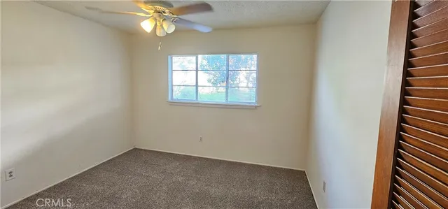 an empty room with windows and fan