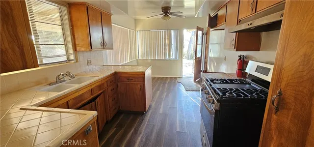 a kitchen with granite countertop a stove a sink dishwasher and cabinets with wooden floor