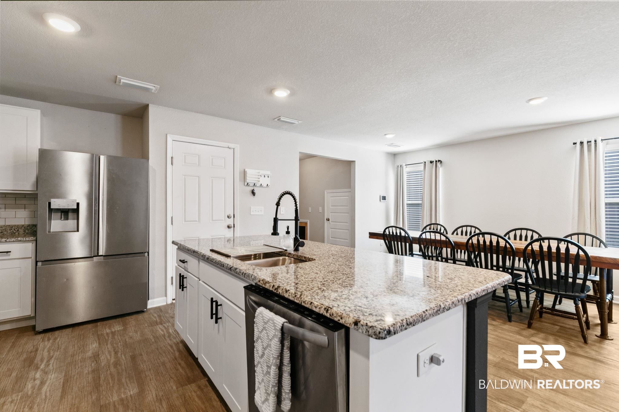 32234 Calder Court Daphne, AL 36527 - Photo 10 of 32 Kitchen featuring stainless steel appliances, white cabinetry, light stone countertops, a center island with sink, and light wood-style flooring