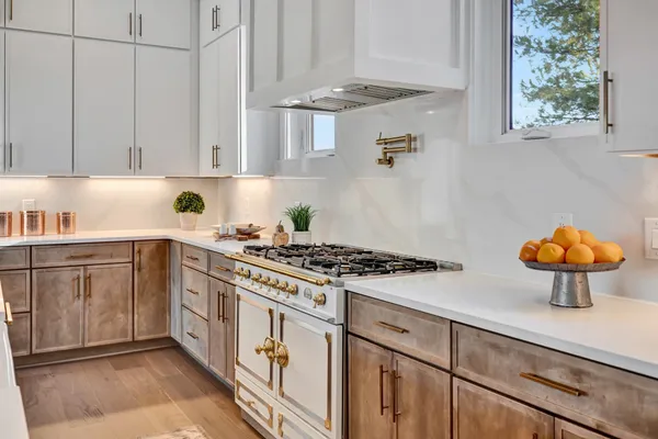 a kitchen with stainless steel appliances granite countertop a stove top oven a sink dishwasher a dining table and chairs with wooden floor