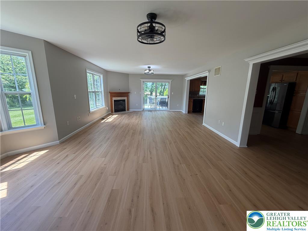 4157 Walter Road Bethlehem, PA 18020 - Photo 10 of 36 An open-concept living space with lustrous hardwood-style flooring, a cozy fireplace, and access to outdoor living.
