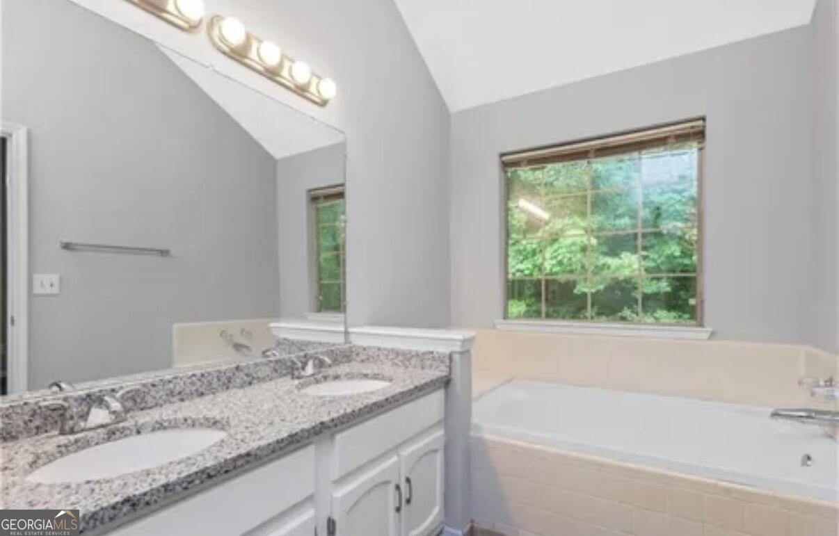 956 Forest Path Stone Mountain, GA 30088 - Photo 11 of 11 a bathroom with a granite countertop bathtub a sink and a large mirror