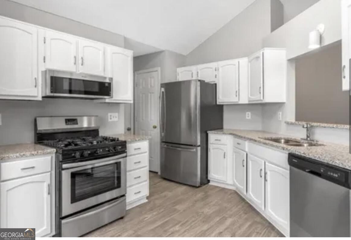 956 Forest Path Stone Mountain, GA 30088 - Photo 5 of 11 a kitchen with stainless steel appliances granite countertop white cabinets a sink a stove a refrigerator and a microwave