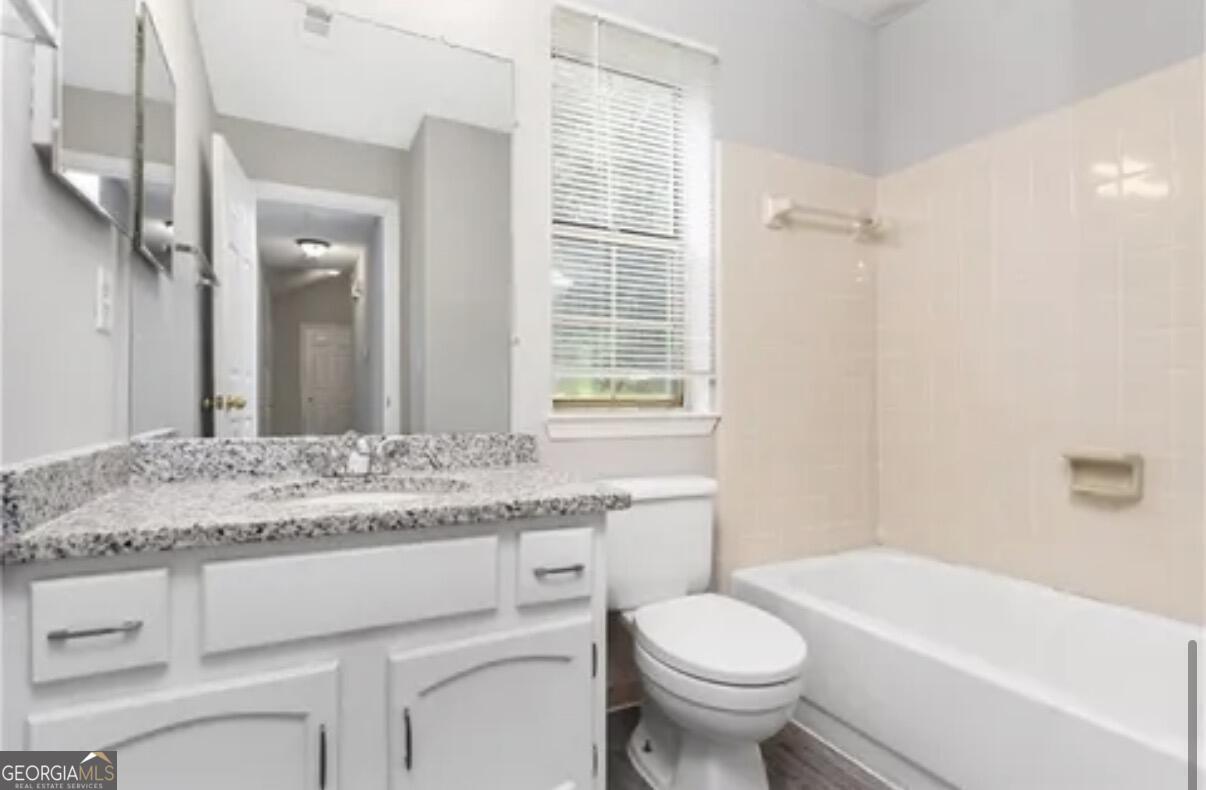 956 Forest Path Stone Mountain, GA 30088 - Photo 9 of 11 a bathroom with a granite countertop toilet a sink and a bathtub