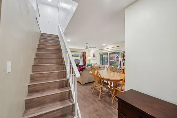 a kitchen with stainless steel appliances kitchen island granite countertop a stove top oven a sink a refrigerator white cabinets and wooden floor