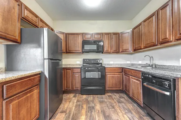a kitchen with granite countertop wooden cabinets a stove top oven and stainless steel appliances