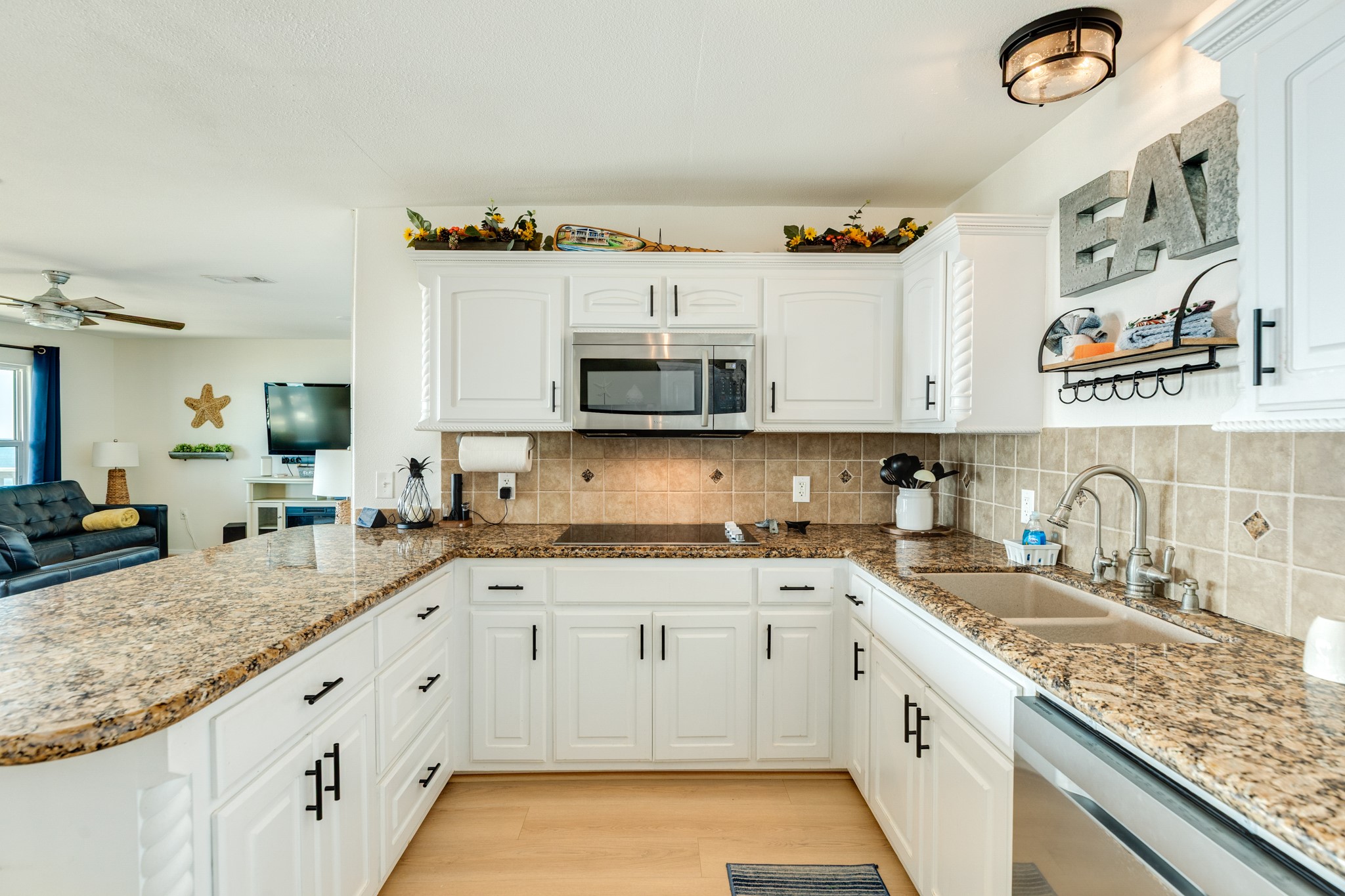210 Beach Drive Surfside Beach, TX 77541 - Photo 11 of 33 Kitchen – Work Zone – White raised-panel cabinetry with black hardware, smooth-surface cooktop, built-in microwave, and generous prep space.