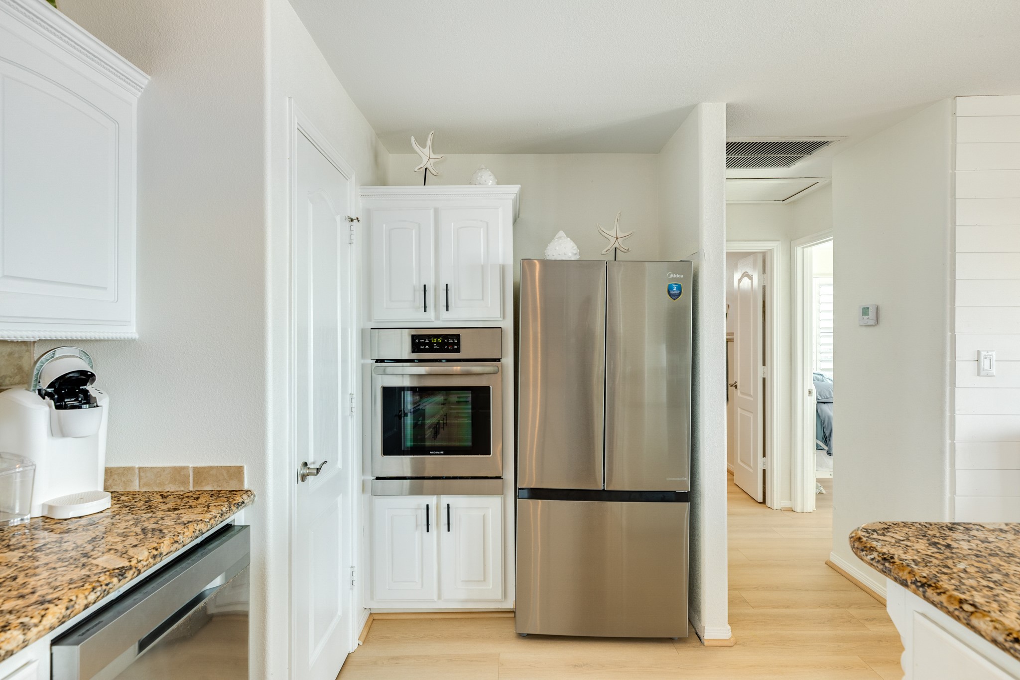 210 Beach Drive Surfside Beach, TX 77541 - Photo 12 of 33 Kitchen – Appliance Wall – Stainless French-door refrigerator and built-in wall oven set beside a pantry cabinet, with easy flow to the bedroom hallway.