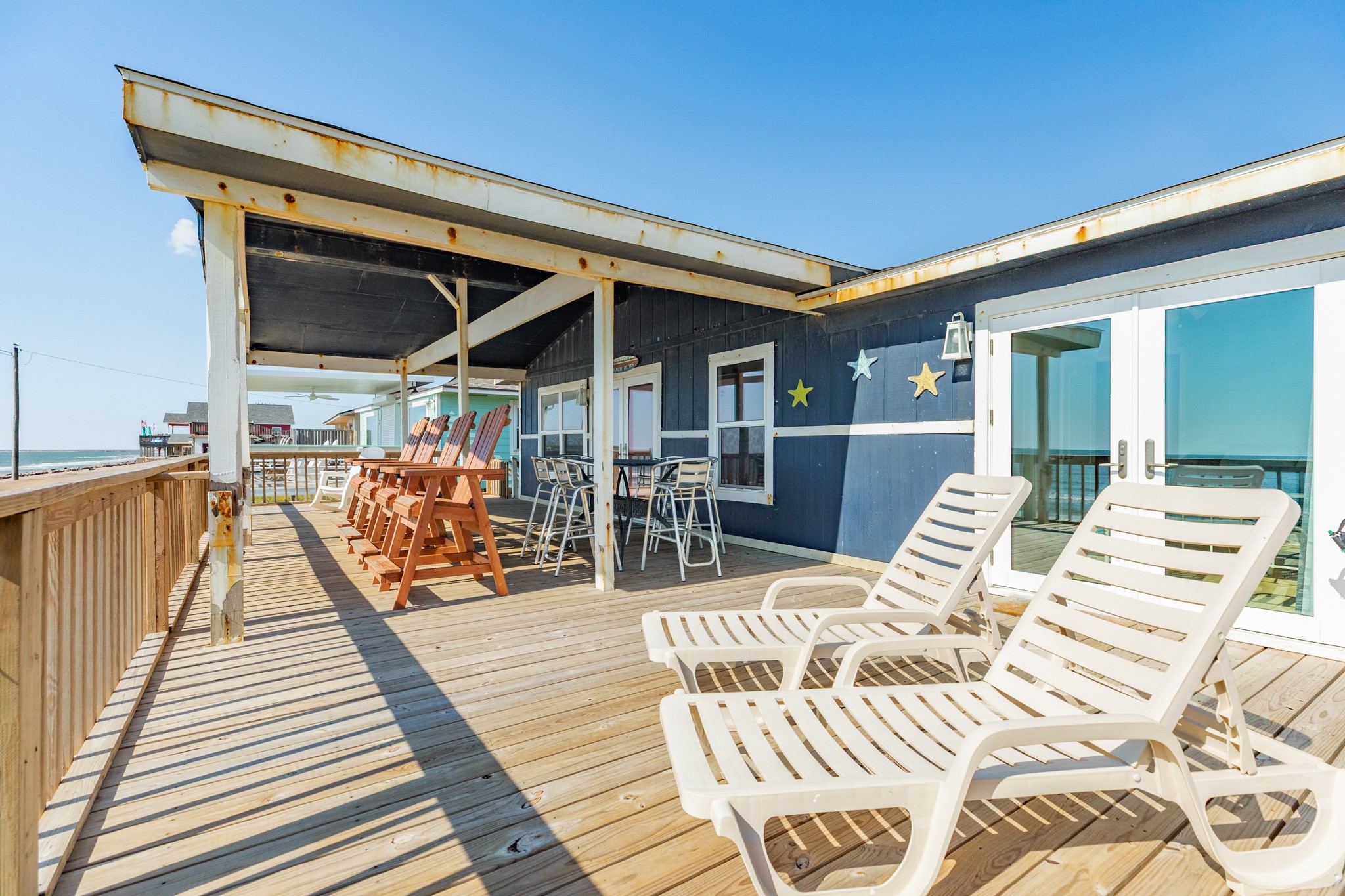 210 Beach Drive Surfside Beach, TX 77541 - Photo 21 of 33 Deck – Multiple Zones – Extended deck spans the length of the home with lounge chairs and conversation areas, plus easy access through double glass doors.