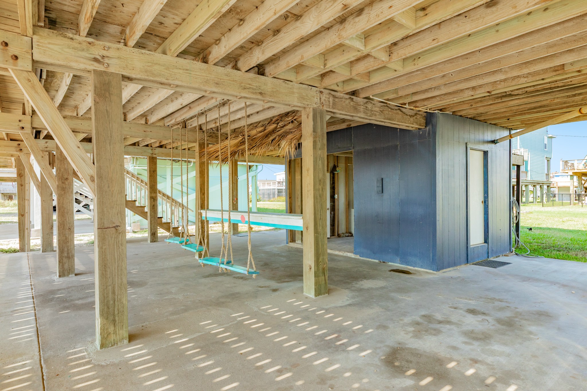 210 Beach Drive Surfside Beach, TX 77541 - Photo 31 of 33 Ground Level – Shaded Hangout – Spacious area under the home with concrete pad, outdoor shower/storage room, and playful bench swings.