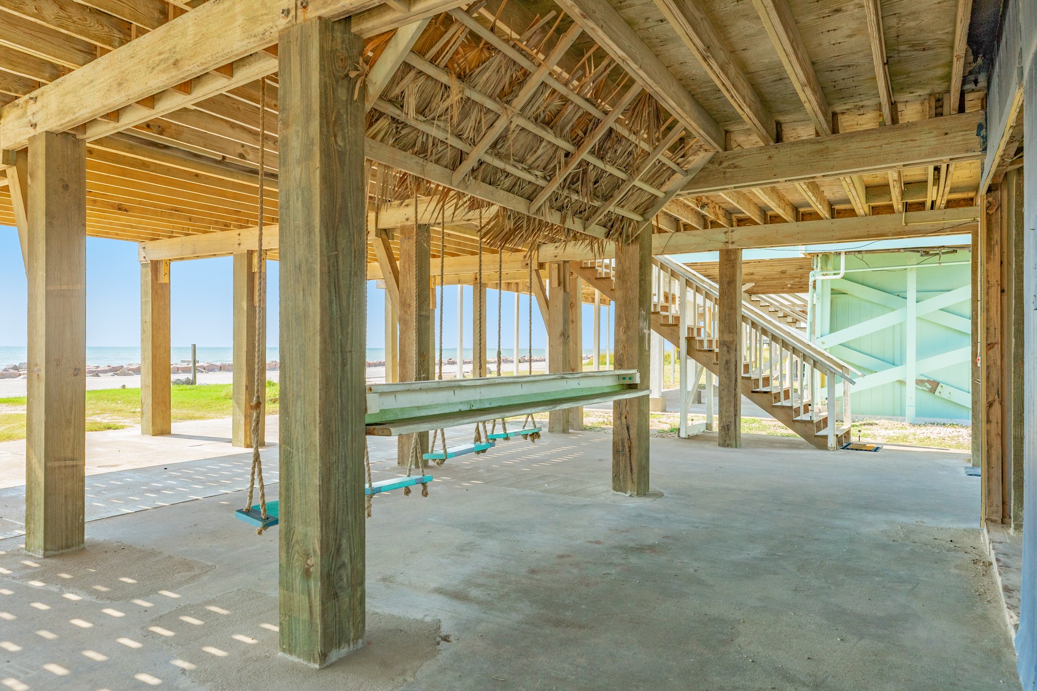210 Beach Drive Surfside Beach, TX 77541 - Photo 32 of 33 Ground Level – Palapa Detail – Tiki-style palapa roof and swing seating create a fun, breezy gathering spot steps from the sand.