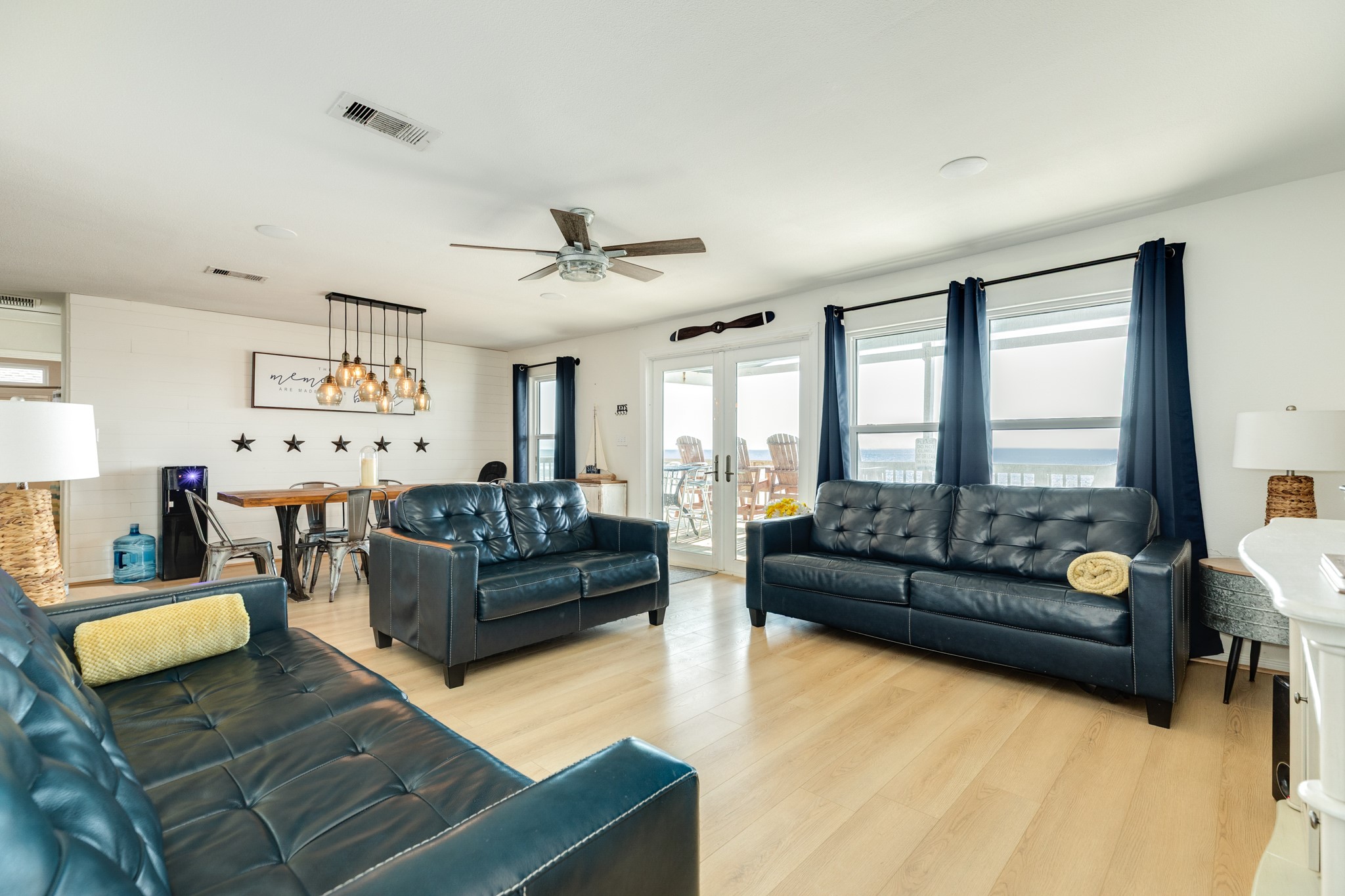 210 Beach Drive Surfside Beach, TX 77541 - Photo 4 of 33 Living/Dining – Open Concept – Seamless gathering space with light plank flooring, multiple windows, and direct deck access for indoor-outdoor entertaining.