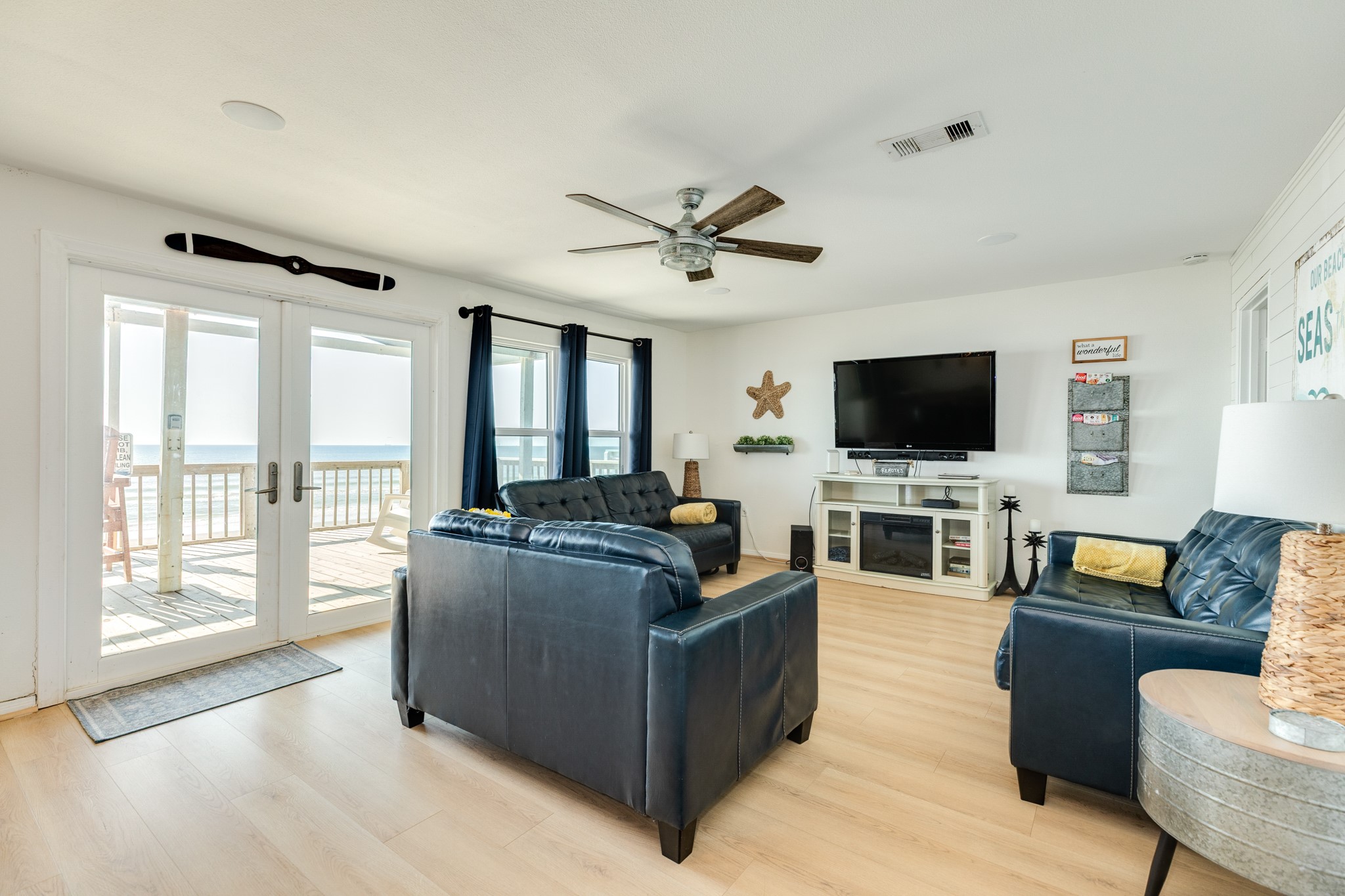 210 Beach Drive Surfside Beach, TX 77541 - Photo 6 of 33 Living Room – Beachfront – Bright coastal living area with double glass doors to the deck, water views, ceiling fan, and media wall with electric fireplace.