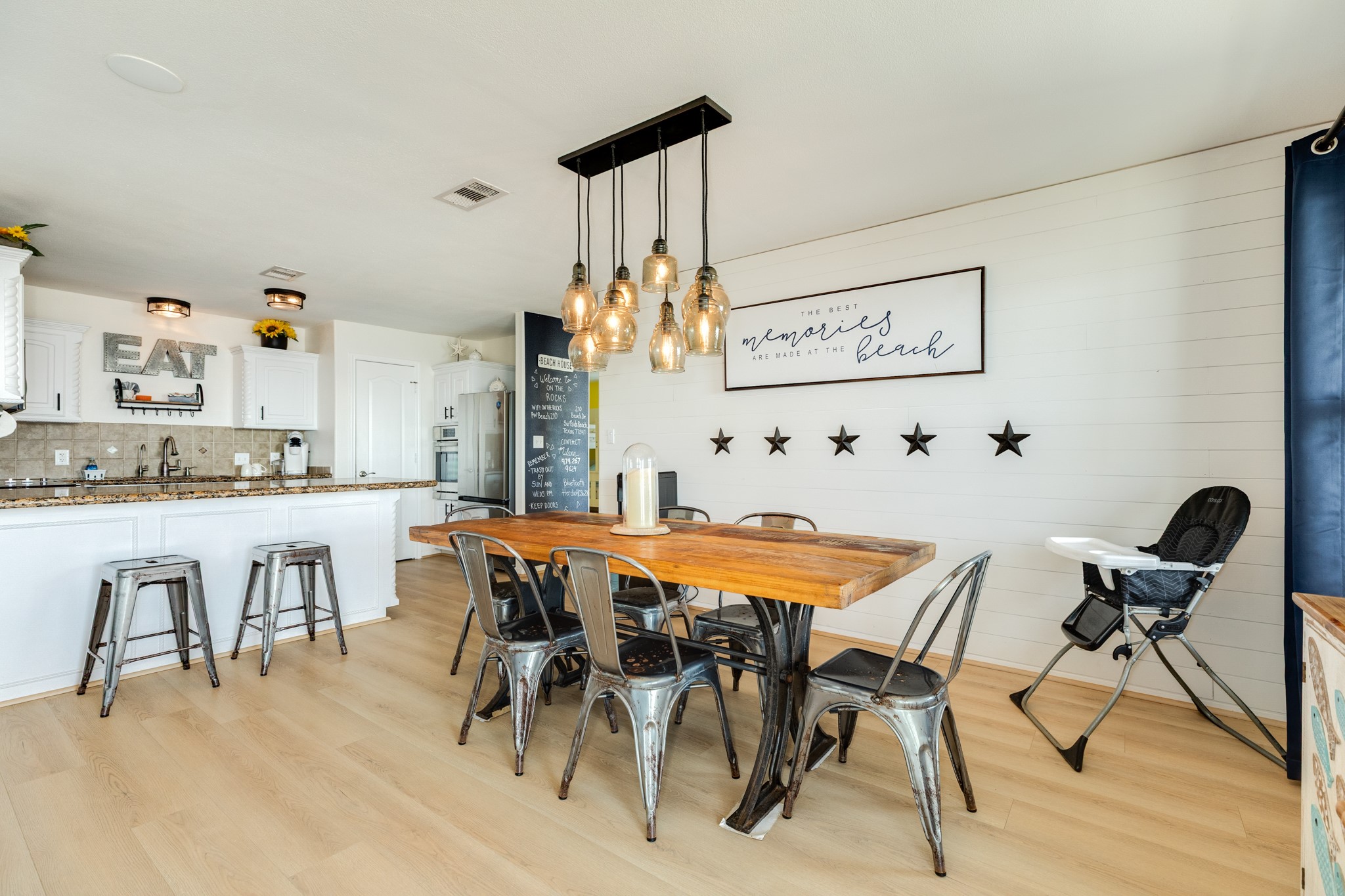 210 Beach Drive Surfside Beach, TX 77541 - Photo 9 of 33 Dining to Kitchen – Open dining area with rustic wood table, statement glass pendants, and shiplap accent wall; seamless flow to the breakfast bar.