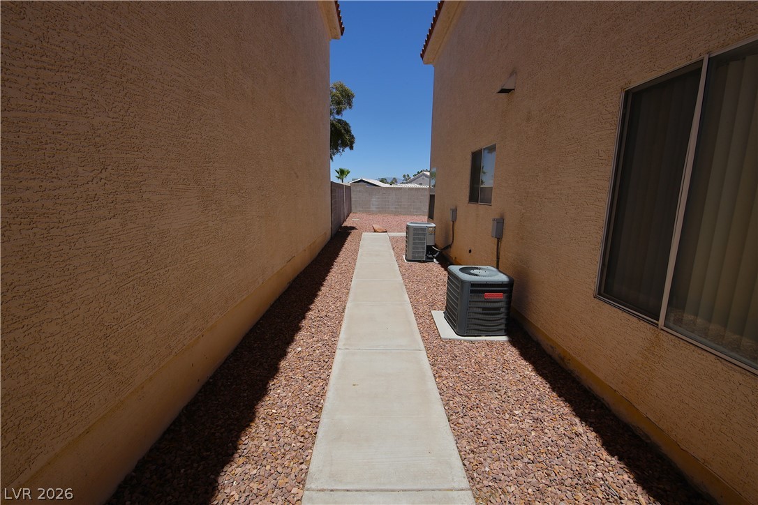 8220 Maplestar Road Las Vegas, NV 89128 - Photo 25 of 29 A well-maintained side yard features a practical concrete walkway bordered by gravel.