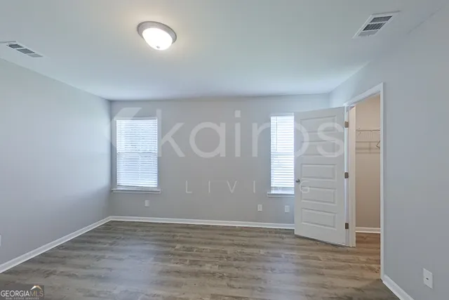 an empty room with wooden floor and windows
