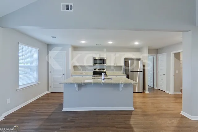 a view of kitchen with stainless steel appliances granite countertop cabinets and wooden floor
