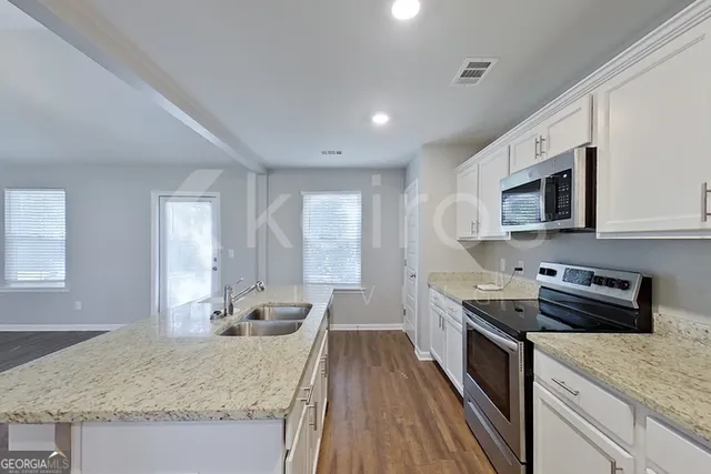 a kitchen with granite countertop stainless steel appliances sink stove microwave and cabinets