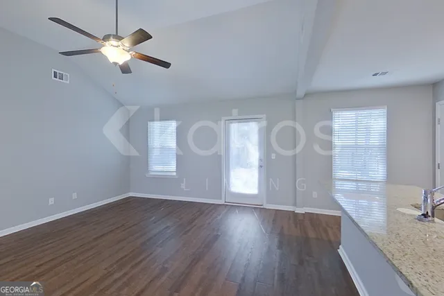 a view of an empty room with a window and wooden floor