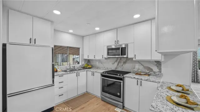 a kitchen with granite countertop cabinets stainless steel appliances and a sink
