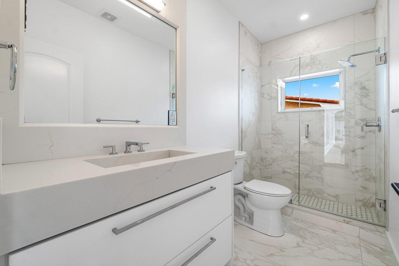 1366 Southwest 4th Court Boca Raton, FL 33432 - Photo 21 of 43 a bathroom with a sink toilet a mirror and shower