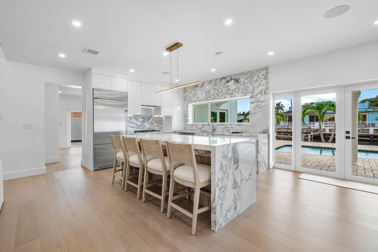 1366 Southwest 4th Court Boca Raton, FL 33432 - Photo 10 of 43 a dining room with stainless steel appliances kitchen island granite countertop a table chairs and a view of living room