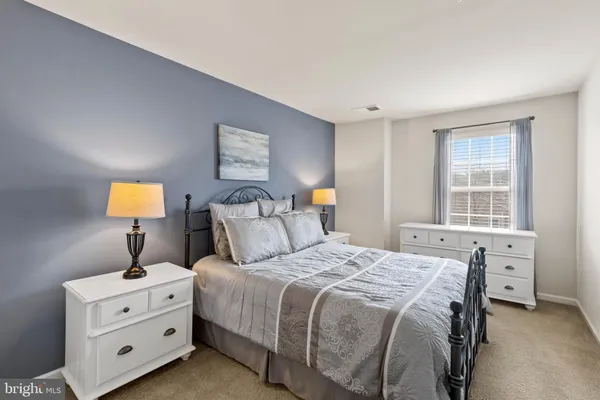 a bedroom with a bed and a lamp on dresser